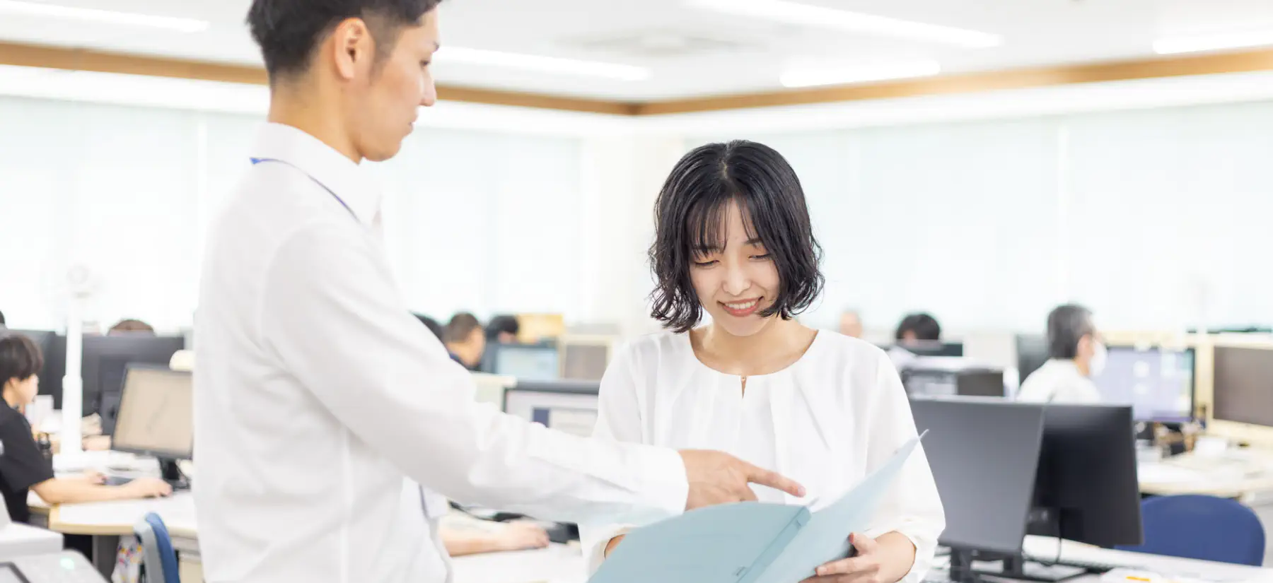 ファイルを見ながら営業職社員と会話する様子